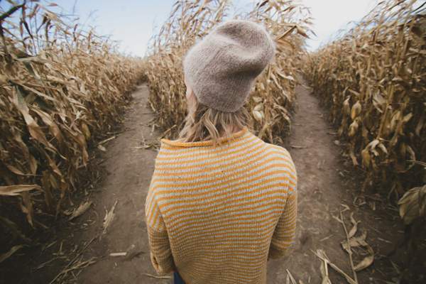 woman standing in a cornfield deciding which path to take